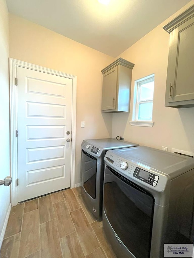 clothes washing area with washer and dryer, light hardwood / wood-style floors, and cabinets