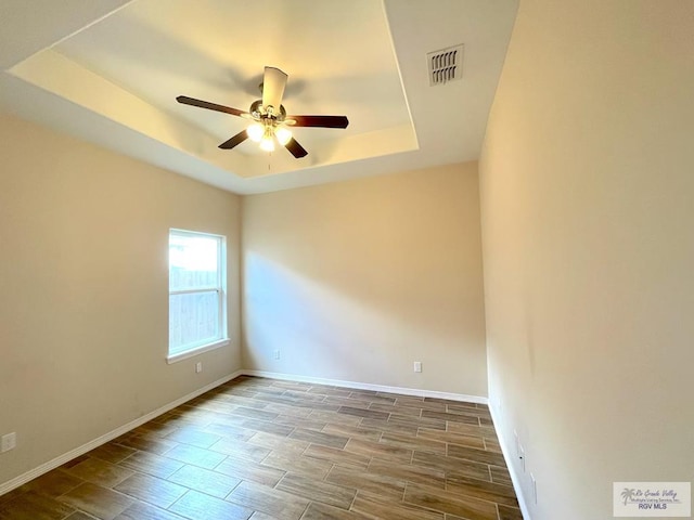 spare room featuring a raised ceiling, ceiling fan, and hardwood / wood-style floors