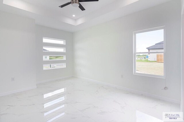 spare room with a tray ceiling and ceiling fan