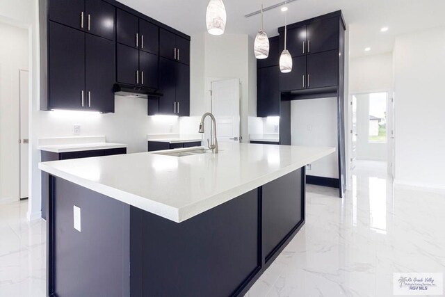 kitchen featuring pendant lighting, sink, and an island with sink