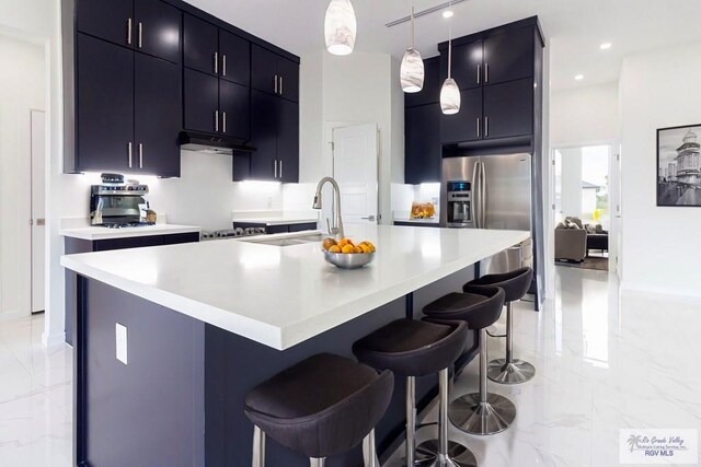 kitchen featuring pendant lighting, sink, a kitchen bar, and an island with sink