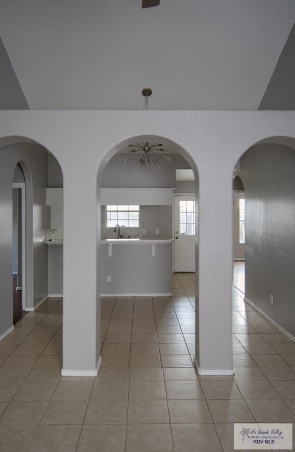 hallway with light tile patterned flooring, lofted ceiling, and sink