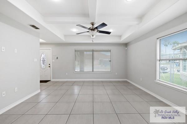 spare room with light tile patterned floors, visible vents, a ceiling fan, baseboards, and beamed ceiling