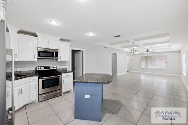 kitchen featuring light tile patterned flooring, white cabinets, open floor plan, appliances with stainless steel finishes, and a center island