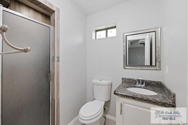 full bath with baseboards, vanity, toilet, and a shower stall