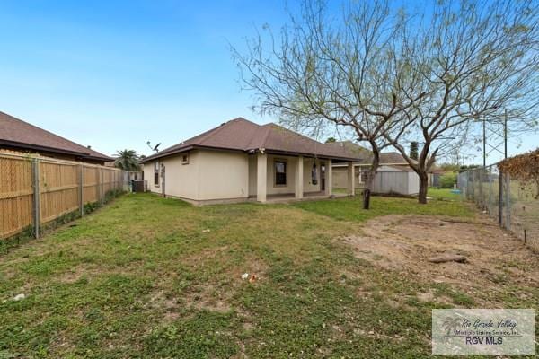 back of property featuring a yard, central AC, a fenced backyard, and stucco siding