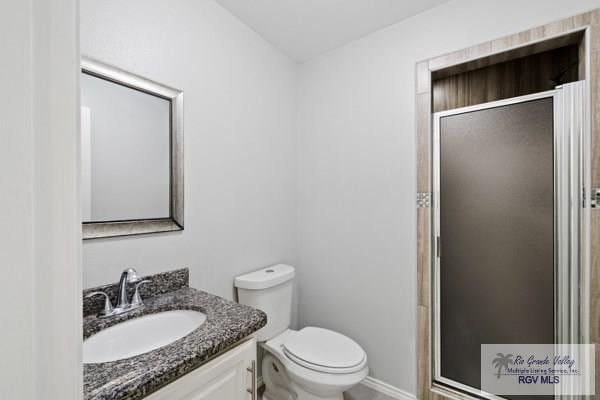 bathroom featuring toilet, a shower stall, and vanity