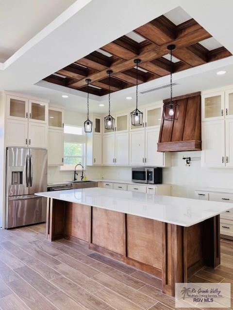 16602 Napper Ln, Primera, TX 78552 - kitchen featuring appliances with stainless steel finishes, a spacious island, coffered ceiling, light wood finished floors, and light countertops
