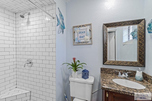 bathroom featuring a tile shower, vanity, and toilet