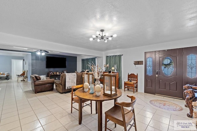 dining space with ceiling fan with notable chandelier, light tile patterned floors, and a textured ceiling