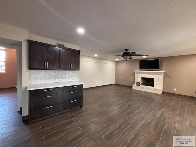 1060 Timothy St, San Benito, TX 78586 - unfurnished living room featuring baseboards, a fireplace, dark wood-style floors, and a ceiling fan