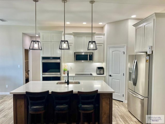 3706 Bea Ave, Harlingen, TX 78552 - kitchen featuring stainless steel appliances, a sink, light wood finished floors, light countertops, and backsplash