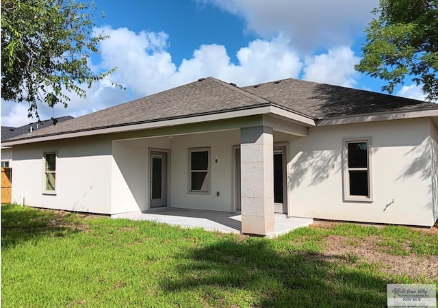rear view of property featuring a patio, roof with shingles, a yard, and stucco siding