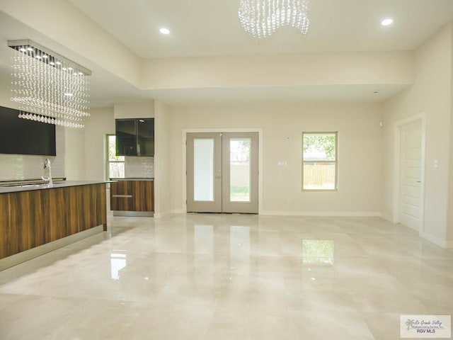 unfurnished living room featuring recessed lighting, french doors, baseboards, and an inviting chandelier
