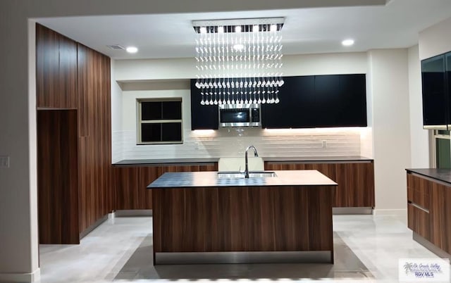 kitchen featuring tasteful backsplash, sink, and an island with sink