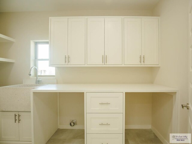 unfurnished office featuring sink and light tile patterned floors