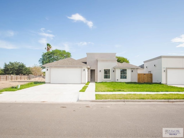 view of front of house featuring stucco siding, a front yard, fence, an attached garage, and driveway
