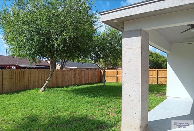 view of yard with a fenced backyard and ceiling fan