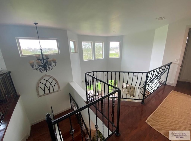 stairs featuring plenty of natural light, a chandelier, and hardwood / wood-style flooring