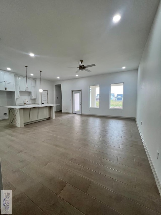 unfurnished living room featuring ceiling fan and hardwood / wood-style flooring