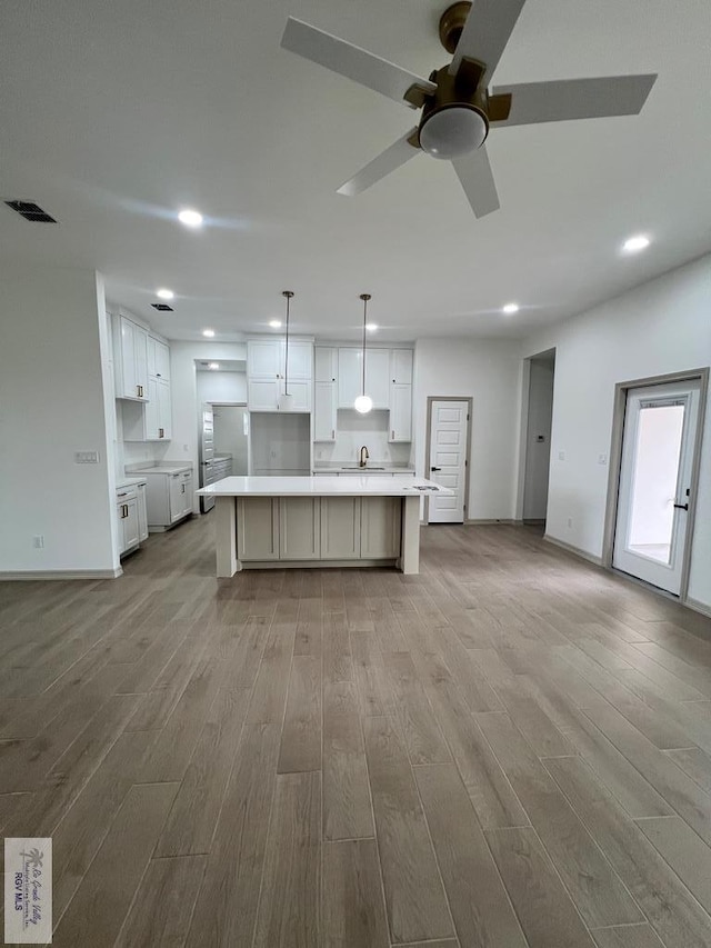 kitchen featuring ceiling fan, white cabinets, a center island, light hardwood / wood-style floors, and hanging light fixtures