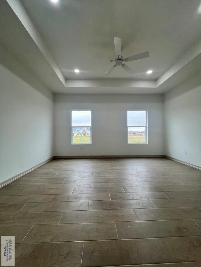 spare room featuring a wealth of natural light, ceiling fan, and dark hardwood / wood-style floors