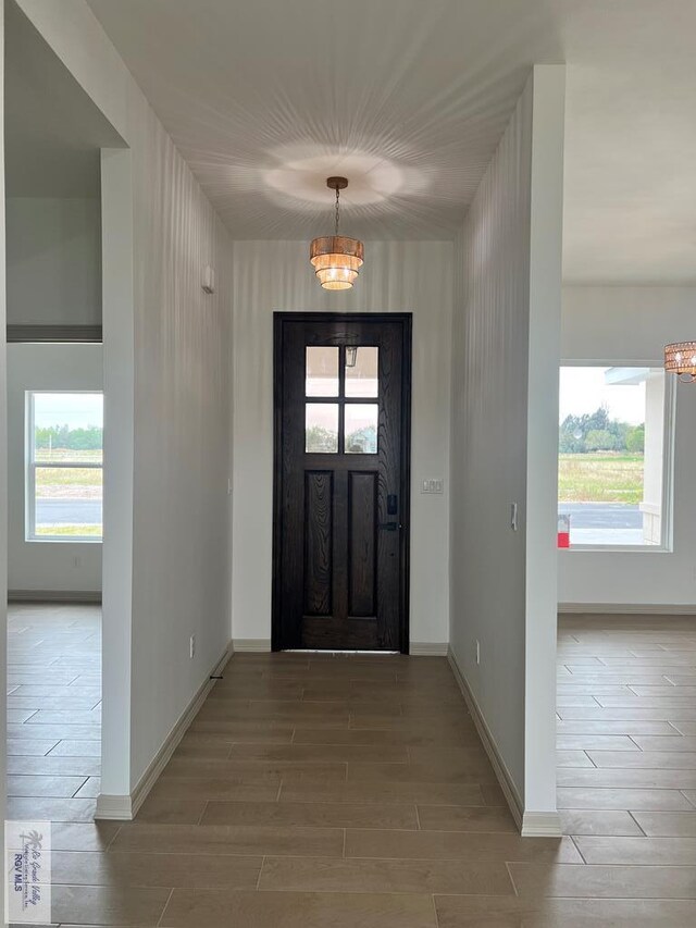 foyer with a notable chandelier, a healthy amount of sunlight, and light wood-type flooring