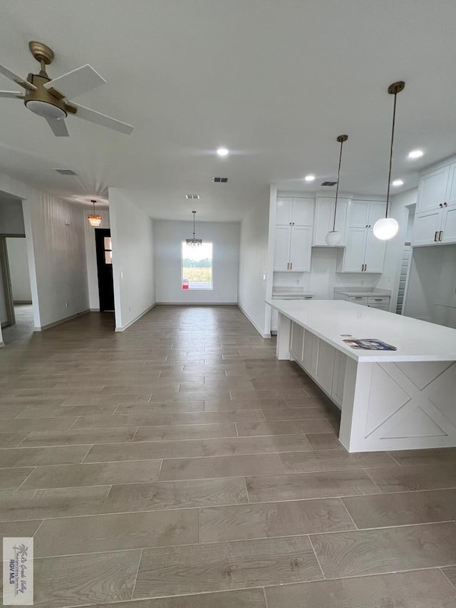 kitchen featuring light hardwood / wood-style flooring, white cabinetry, hanging light fixtures, and ceiling fan