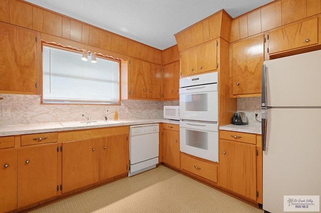 kitchen with light floors, light countertops, decorative backsplash, white appliances, and a sink