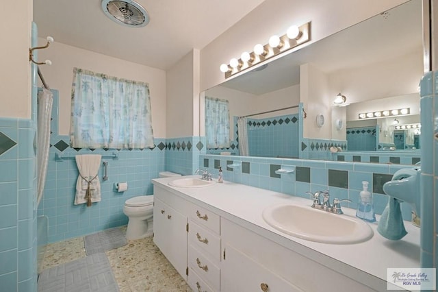 7969 Fm 2099, Lyford, TX 78580 - bathroom with double vanity, tiled shower, toilet, tile walls, and wainscoting