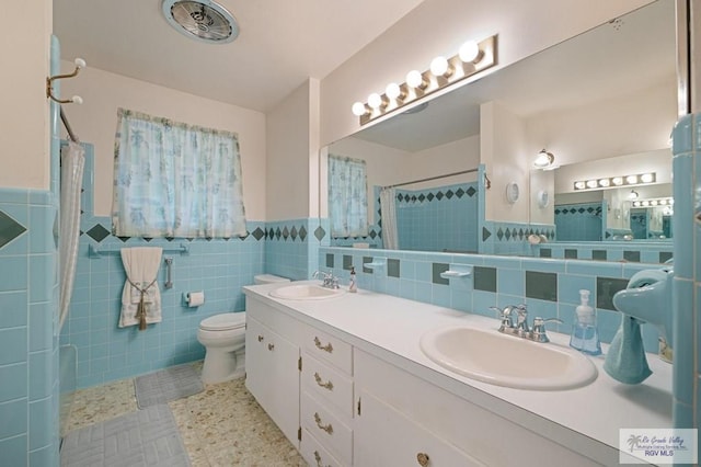 full bathroom with toilet, tile walls, a shower with shower curtain, and a sink