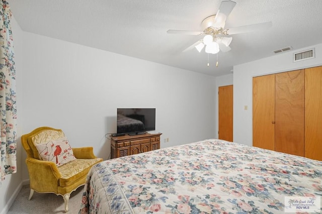 bedroom with carpet flooring, visible vents, a closet, and a textured ceiling