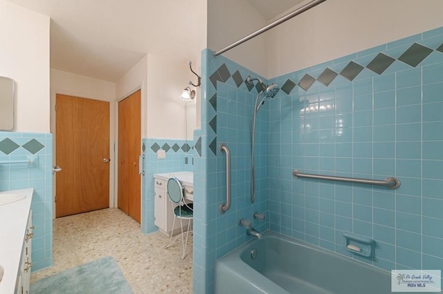 full bath featuring vanity, tile walls, a wainscoted wall, and shower / washtub combination