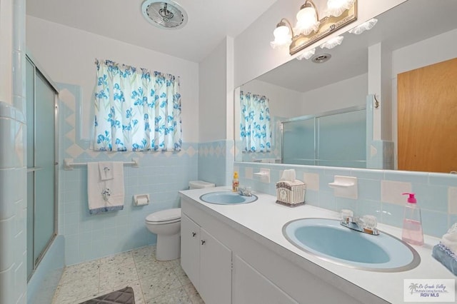 7969 Fm 2099, Lyford, TX 78580 - bathroom featuring double vanity, tile walls, a wainscoted wall, and bath / shower combo with glass door