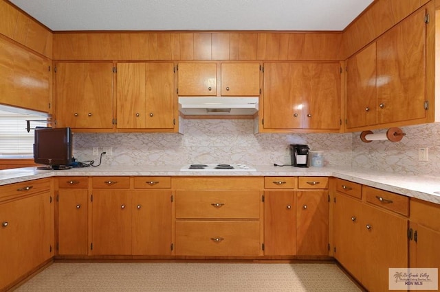 kitchen with under cabinet range hood, light floors, light countertops, decorative backsplash, and white cooktop