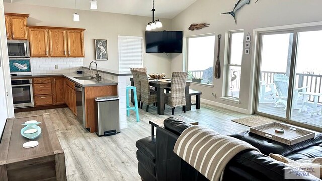 kitchen featuring sink, hanging light fixtures, stainless steel appliances, decorative backsplash, and vaulted ceiling