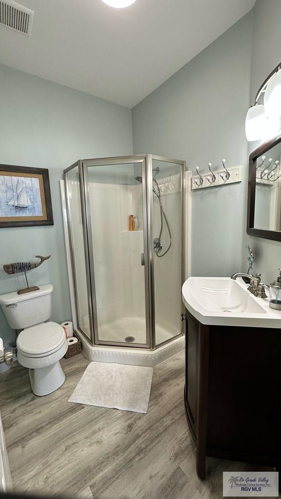 bathroom with vanity, lofted ceiling, hardwood / wood-style floors, and a shower with shower door