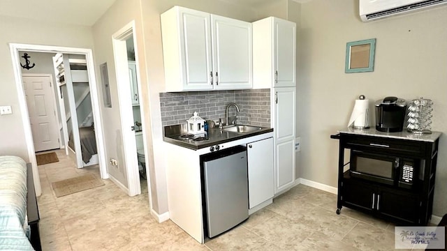 kitchen with sink, tasteful backsplash, refrigerator, a wall mounted AC, and white cabinets