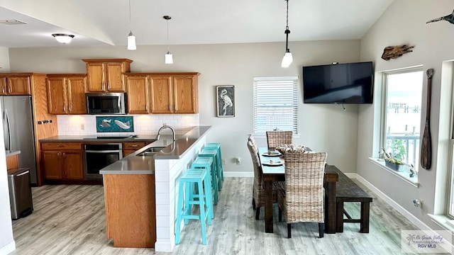 kitchen with sink, decorative light fixtures, appliances with stainless steel finishes, a kitchen breakfast bar, and backsplash