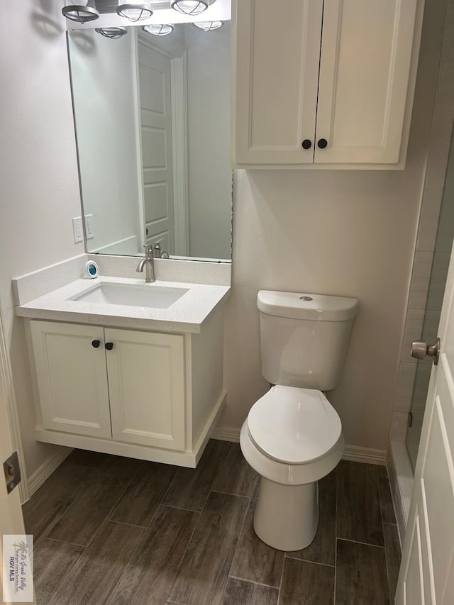 bathroom with toilet, vanity, and hardwood / wood-style flooring