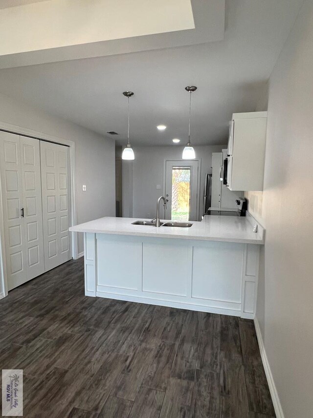 kitchen featuring white cabinetry, sink, dark hardwood / wood-style floors, kitchen peninsula, and pendant lighting