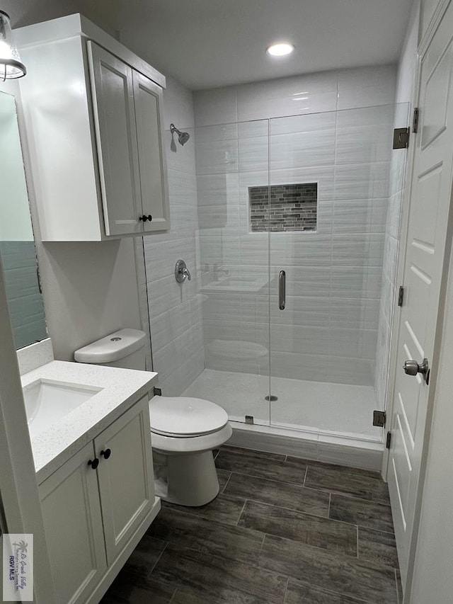 bathroom featuring vanity, toilet, and a shower with door