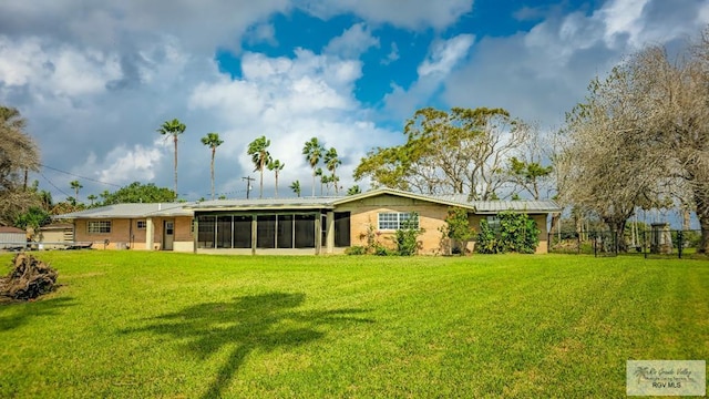 rear view of property with a sunroom and a lawn