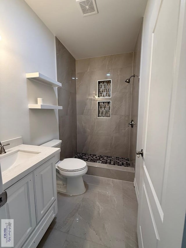 139 Heron Dr, Los Fresnos, TX 78566 - bathroom featuring marble finish floors, a tile shower, and vanity
