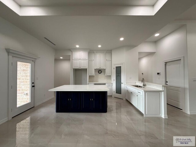 139 Heron Dr, Los Fresnos, TX 78566 - kitchen with light marble finish flooring, white cabinetry, recessed lighting, a kitchen island, and light countertops