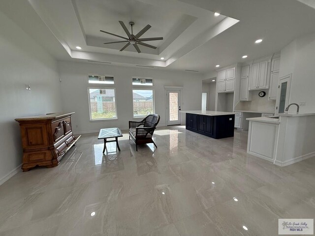 139 Heron Dr, Los Fresnos, TX 78566 - living area featuring light marble finish floors, a ceiling fan, a raised ceiling, and recessed lighting