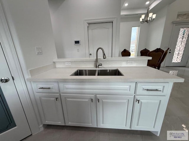 139 Heron Dr, Los Fresnos, TX 78566 - kitchen featuring light countertops, white cabinets, a chandelier, and a peninsula
