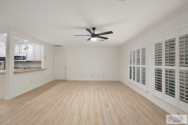 unfurnished living room with light wood-type flooring, ceiling fan, and crown molding