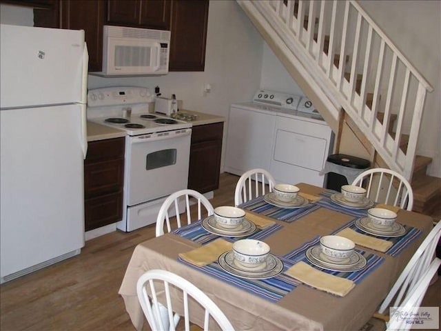 kitchen featuring white appliances, hardwood / wood-style flooring, dark brown cabinetry, and washing machine and clothes dryer