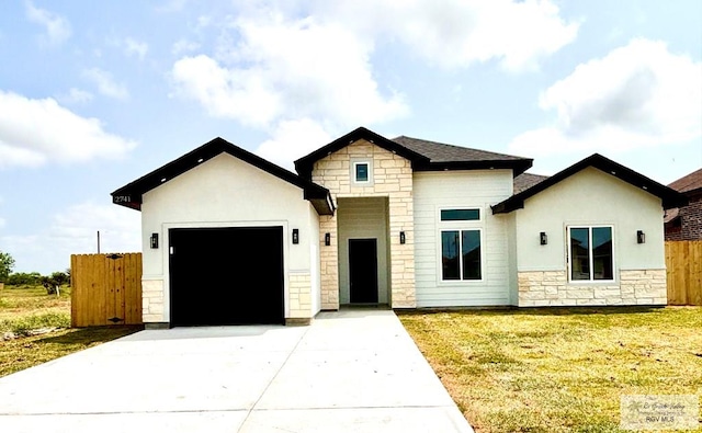 view of front of house featuring a front lawn, driveway, stone siding, an attached garage, and fence